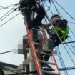 Petugas PLN saat mengevakuasi tubuh korban yang tergantung di tiang listrik. (foto: dok. Polsek Kertapati)