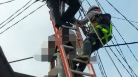 Petugas PLN saat mengevakuasi tubuh korban yang tergantung di tiang listrik. (foto: dok. Polsek Kertapati)