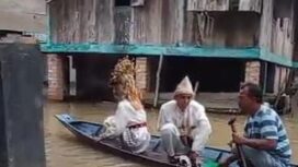 Sepasang pengantin di PALI saat menaiki perahu yang dikemudikan kerabat untuk mencapai tempat pelaminan. Foto : Istimewa