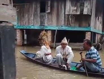Sepasang pengantin di PALI saat menaiki perahu yang dikemudikan kerabat untuk mencapai tempat pelaminan. Foto : Istimewa