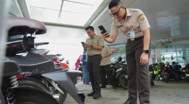 Kepala Bapenda Sumsel Ahmad Rizwan saat mengecek pajak kendaraan yang sedang parkir. Foto : Bapenda Sumsel
