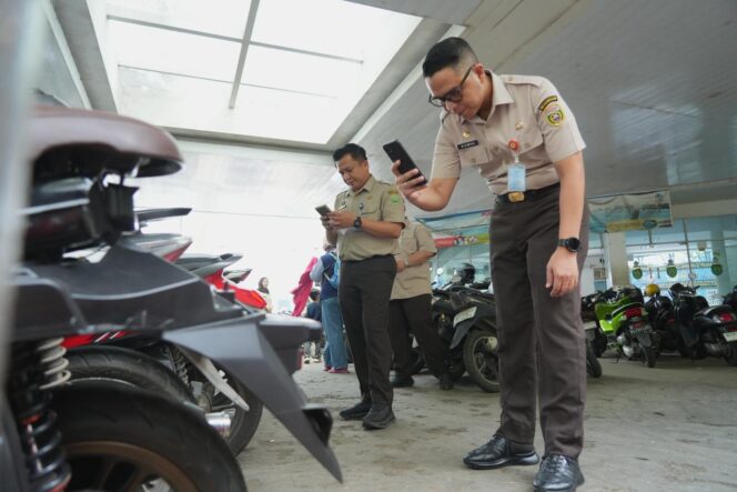 
Kepala Bapenda Sumsel Ahmad Rizwan saat mengecek pajak kendaraan yang sedang parkir. Foto : Bapenda Sumsel