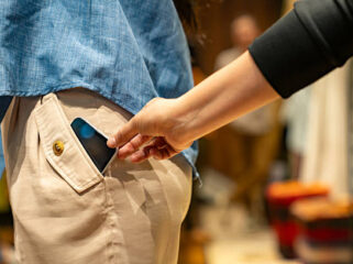 Close-up on a thief stealing a cell phone of a customer at a shopping store - pickpocketing concepts