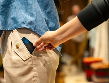 Close-up on a thief stealing a cell phone of a customer at a shopping store - pickpocketing concepts